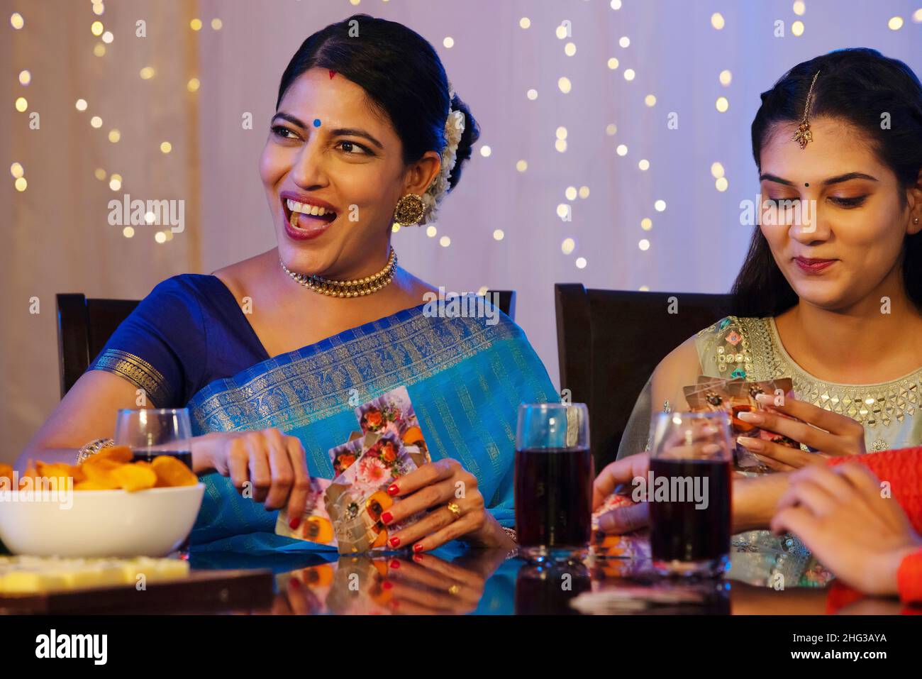 Familienmitglieder haben Spaß beim Kartenspielen auf dem Esstisch anlässlich des Diwali Stockfoto