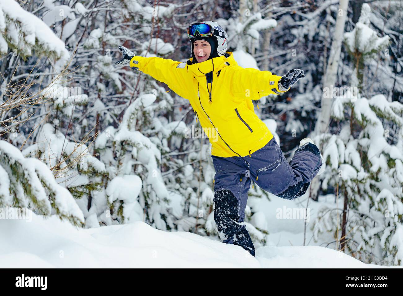 Nette glückliche junge Frau Snowboarder in hellen Kleidern macht lustige Pose im verschneiten Snowboardpark. Erholung im Winter im Freien. Spaß im Schnee. Lifestyle Stockfoto