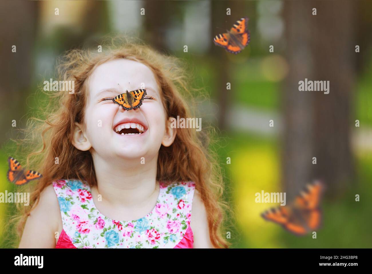 Lustig lachend lockiges Mädchen mit einem Schmetterling auf der Nase. Gesundes Lächeln mit weißen Zähnen. Konzept der freien Atmung. Stockfoto