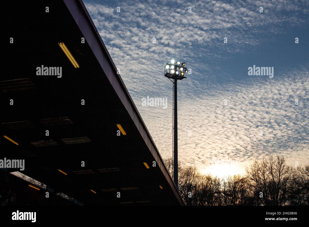 Silhouette von Flutlicht im Fußballstadion gegen Cirrocumulus Wolken bei Sonnenuntergang. VEREINIGTES KÖNIGREICH Stockfoto