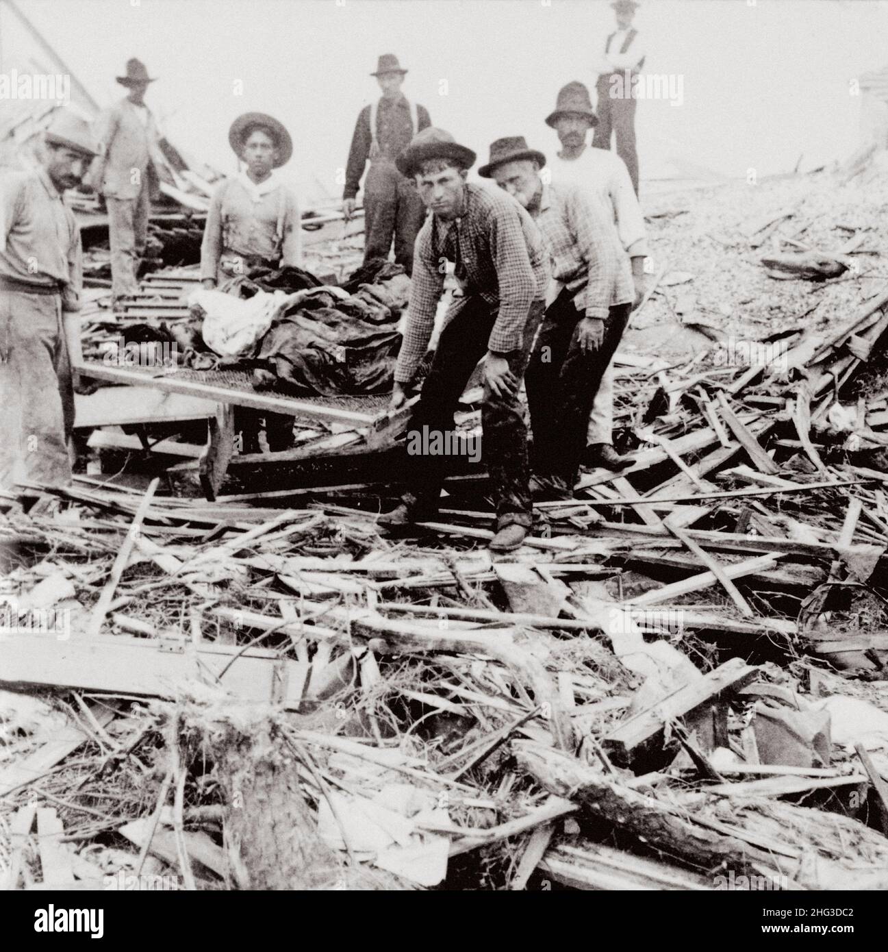 Archivfoto des Hurrikans Galveston 1900. Menschen, die Leichen auf einer Bahre zwischen den Gebäuden tragen, die durch den Hurrikan und die Flut zerstört wurden. Galveston, T Stockfoto