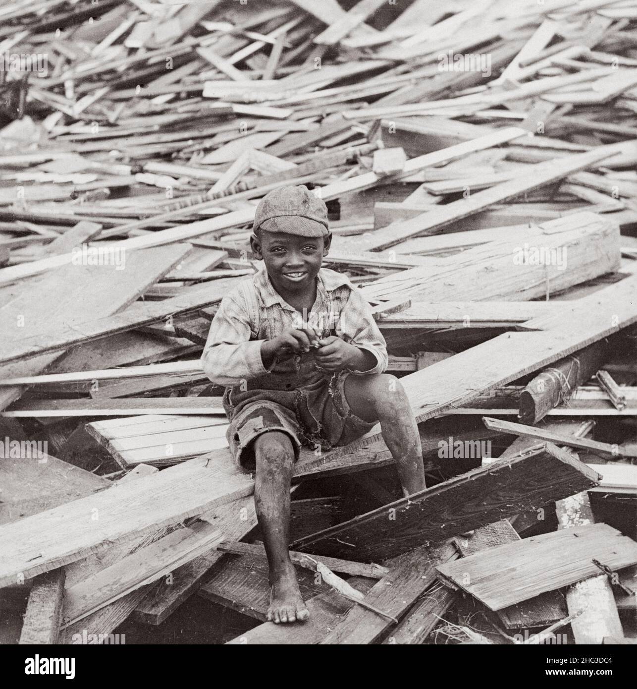 Archivfoto des Hurrikans Galveston 1900. Ein überlebender afroamerikanischer Junge sitzt inmitten der Trümmer, die durch den Hurrikan verursacht wurden. Galveston, Texas. USA. Okt Stockfoto