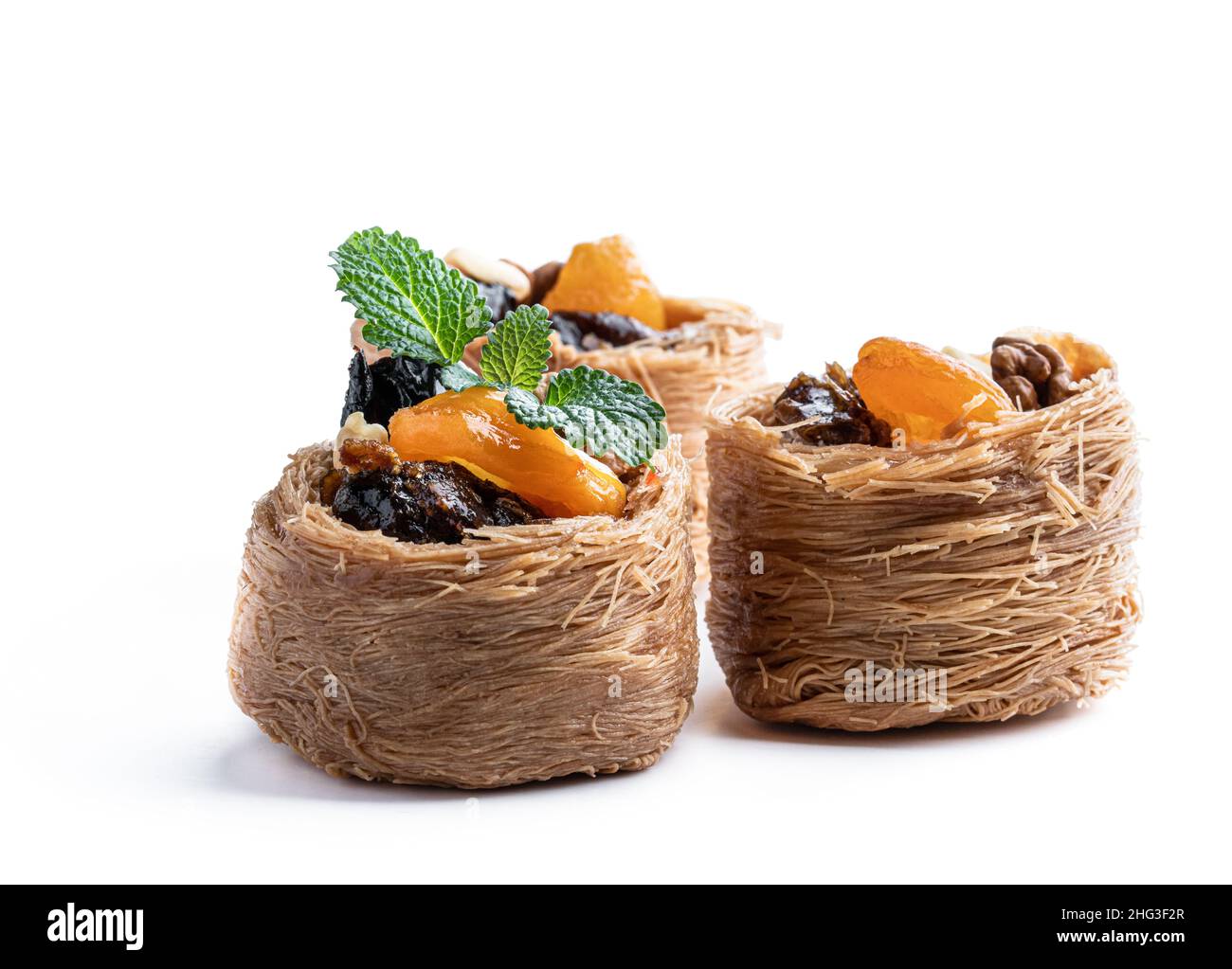 Traditionelle arabische und türkische Süßigkeiten Gebäck Dessert Kadaif mit Nüssen und getrockneten gesüßten Früchten isoliert auf weiß Stockfoto