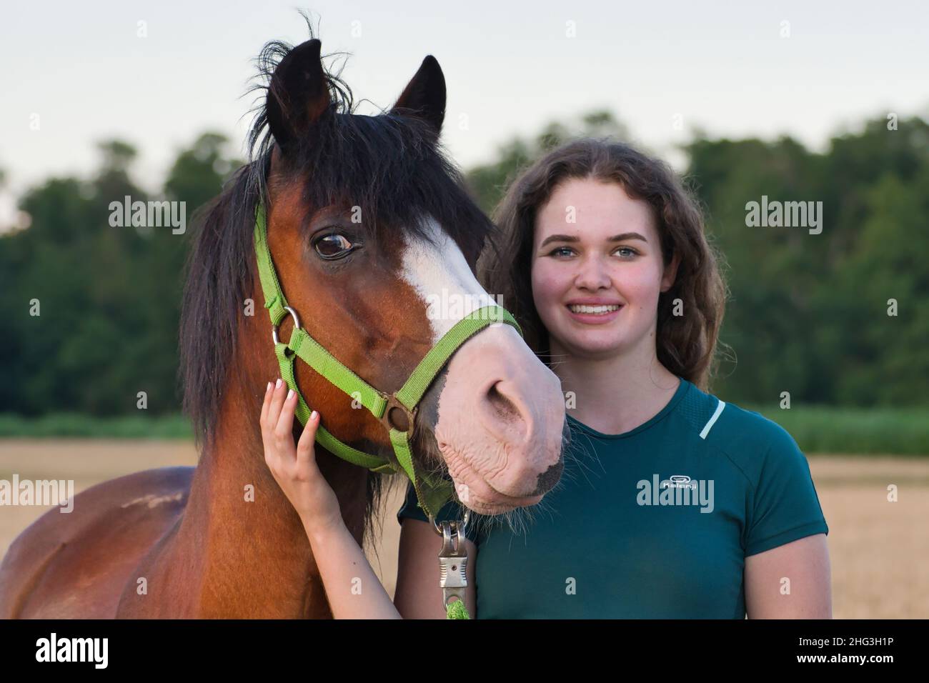 Porträt eines lächelnden kaukasischen Teenagers mit einem hübschen Bay Pony. Stockfoto