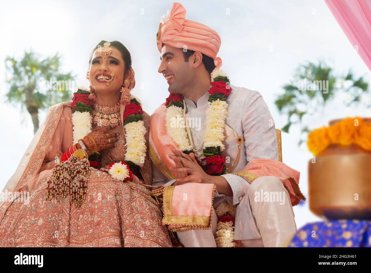 Glückliche indische Braut und Bräutigam sitzen zusammen bei Hochzeit mandap Stockfoto