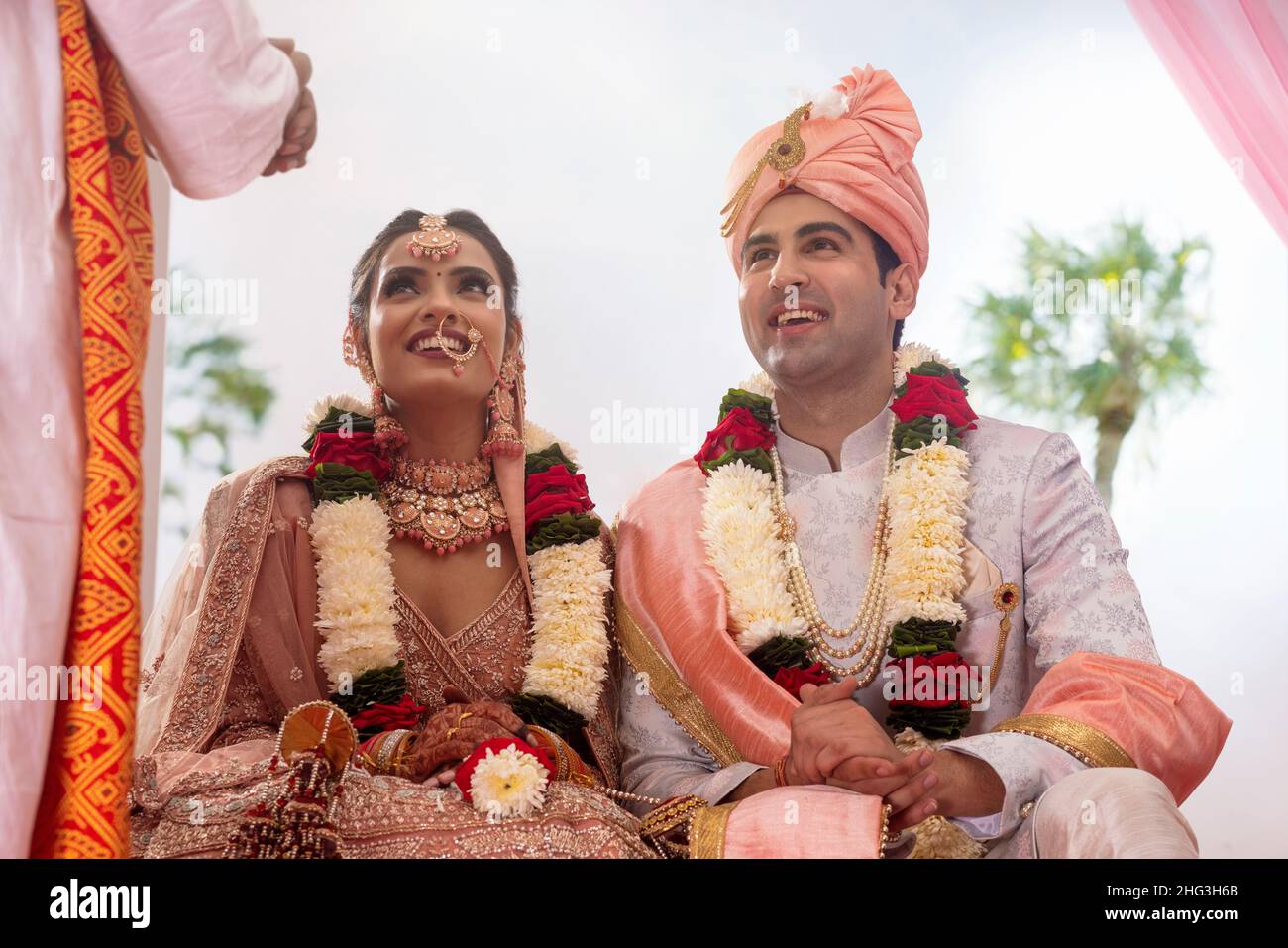 Glückliche indische Braut und Bräutigam sitzen zusammen bei Hochzeit mandap Stockfoto