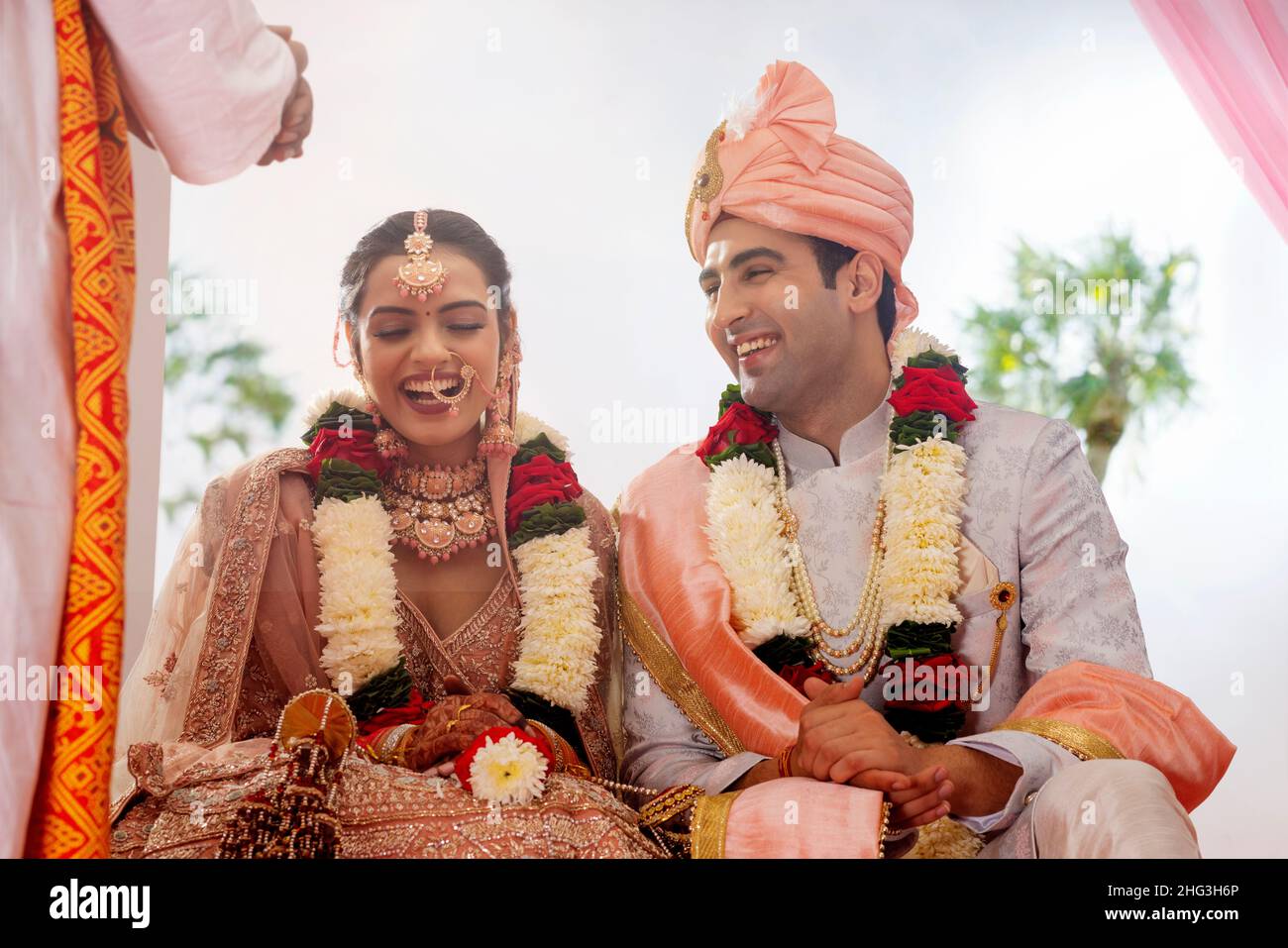 Glückliche indische Braut und Bräutigam sitzen zusammen bei Hochzeit mandap Stockfoto