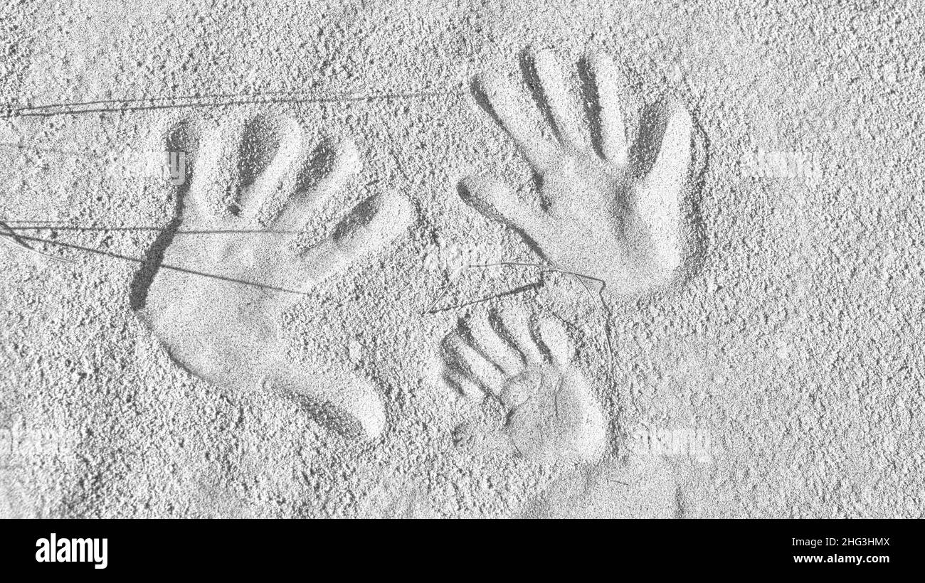 Handabdrücke im Sand am Ostseestrand in Schwarz und Weiß. Verbundenheit einer Familie mit Vater, Mutter und Kind. Symbol von Togethern Stockfoto