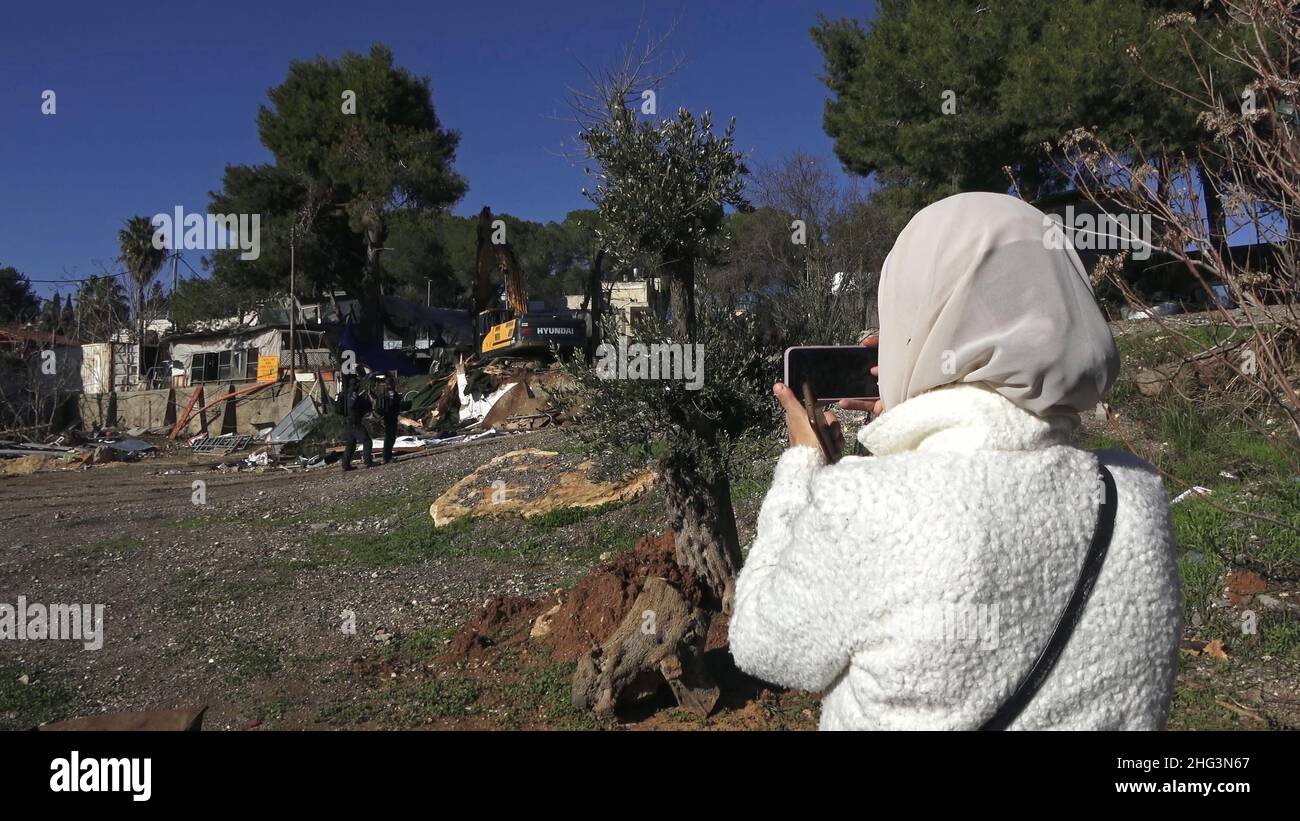 Jerusalem, Israel. 17th Januar 2022. Eine Palästinenserin fotografiert einen Bagger, der eine Struktur auf dem Gelände des Familienhauses eines Palästinensers, Salhiya, zerstört, die am 17. Januar 2021 in Jerusalem, Israel, im Scheich-Jarrah-Viertel geräumt werden soll. Salhiyas Familie ist seit 2017 mit einer Räumungsdrohung konfrontiert, als das Land, in dem sich sein Haus befindet, für den Schulbau bestimmt wurde. Das palästinensische Viertel Sheikh Jarrah ist derzeit das Zentrum einer Reihe von Eigentumsstreitigkeiten zwischen Palästinensern und rechtsgerichteten jüdischen Israelis. Einige Häuser waren besetzt Stockfoto