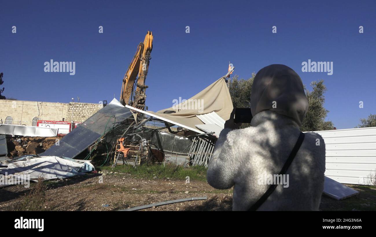 Jerusalem, Israel. 17th Januar 2022. Eine Palästinenserin fotografiert einen Bagger, der eine Struktur auf dem Gelände des Familienhauses eines Palästinensers, Salhiya, zerstört, die am 17. Januar 2021 in Jerusalem, Israel, im Scheich-Jarrah-Viertel geräumt werden soll. Salhiyas Familie ist seit 2017 mit einer Räumungsdrohung konfrontiert, als das Land, in dem sich sein Haus befindet, für den Schulbau bestimmt wurde. Das palästinensische Viertel Sheikh Jarrah ist derzeit das Zentrum einer Reihe von Eigentumsstreitigkeiten zwischen Palästinensern und rechtsgerichteten jüdischen Israelis. Einige Häuser waren besetzt Stockfoto