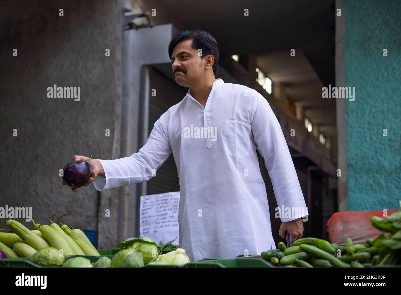 Mann mittleren Alters, der auf dem Markt Brinjal kauft Stockfoto