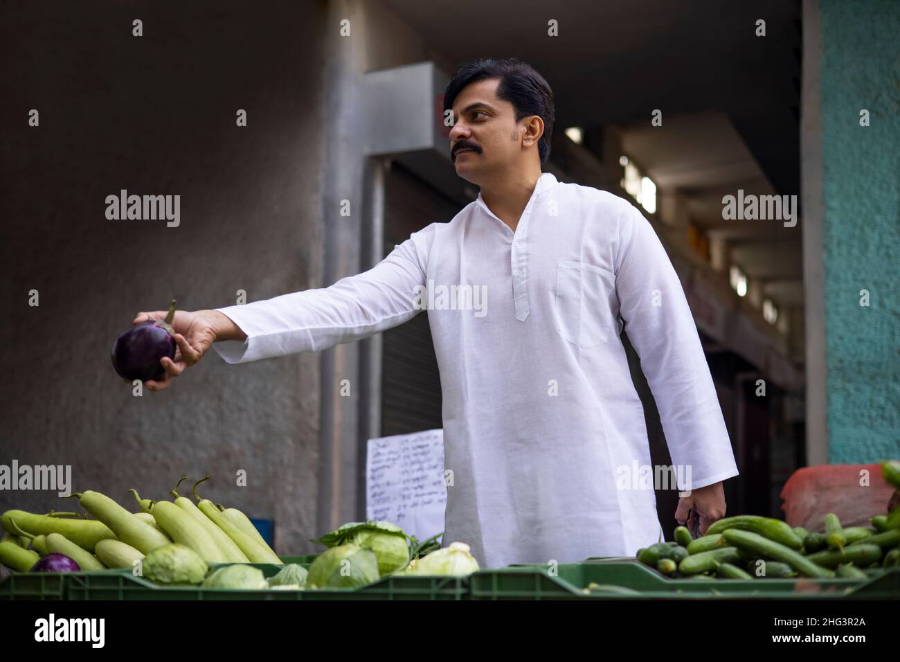 Mann mittleren Alters, der auf dem Markt Brinjal kauft Stockfoto