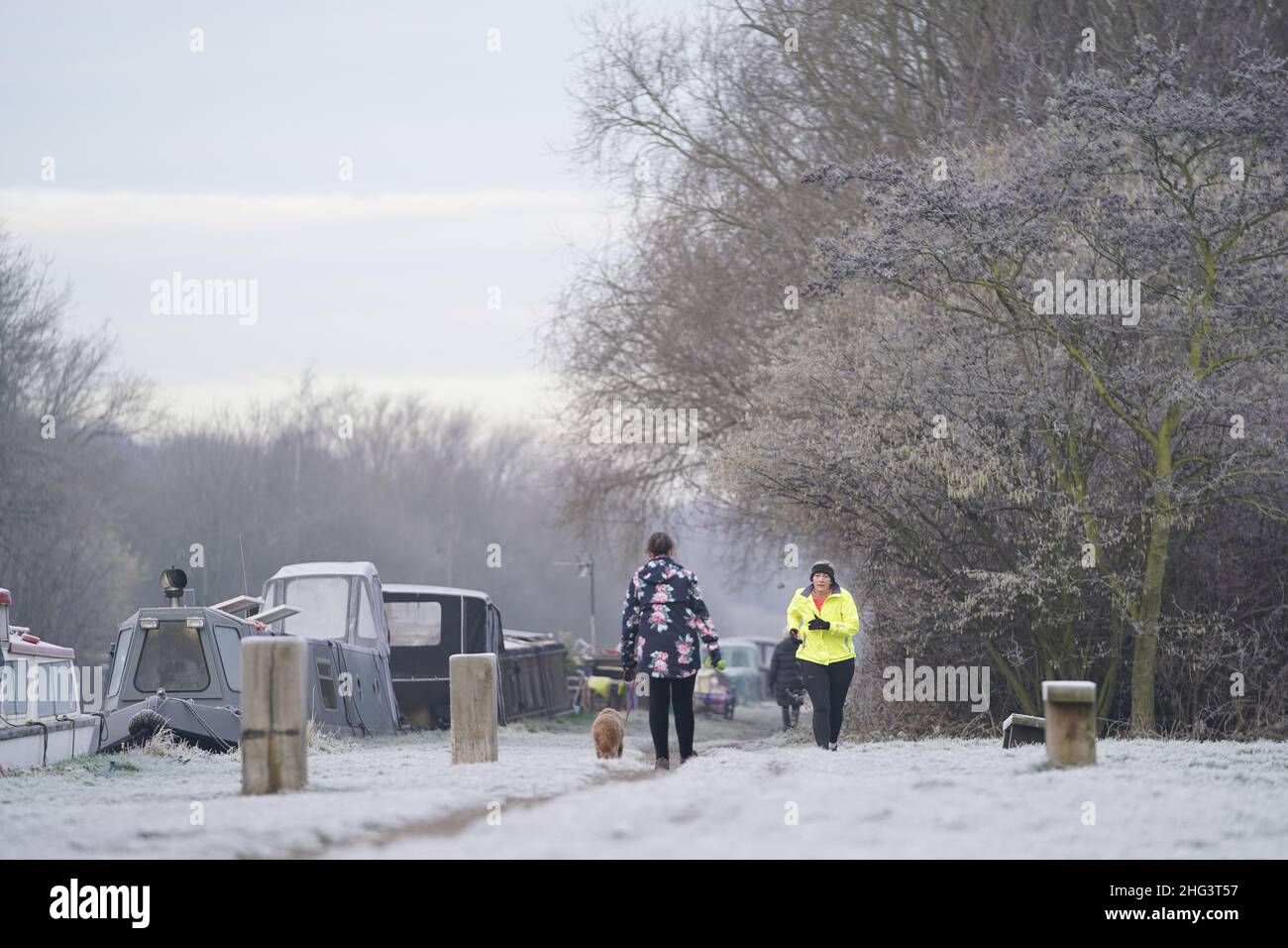 Eine Frau joggt in Woodlesford Lock, Yorkshire, an Kanalbooten mit hartem Frost vorbei. Bilddatum: Dienstag, 18. Januar 2022. Stockfoto