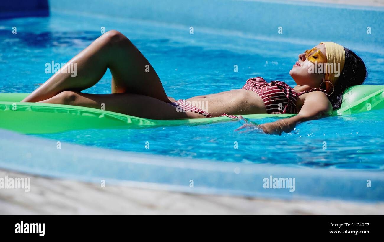 Junge Frau mit Sonnenbrillen schwimmt im Pool Stockfoto