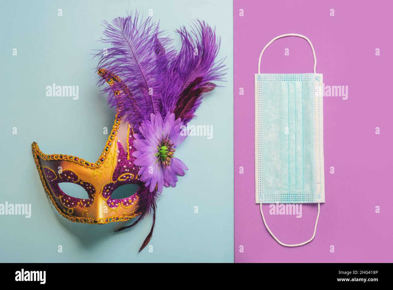 Konzept des Karnevals während des Covid-19. Venezianische Karnevalsmaske mit schützender OP-Maske auf blauem und violettem Hintergrund. Karneval Feier concep Stockfoto