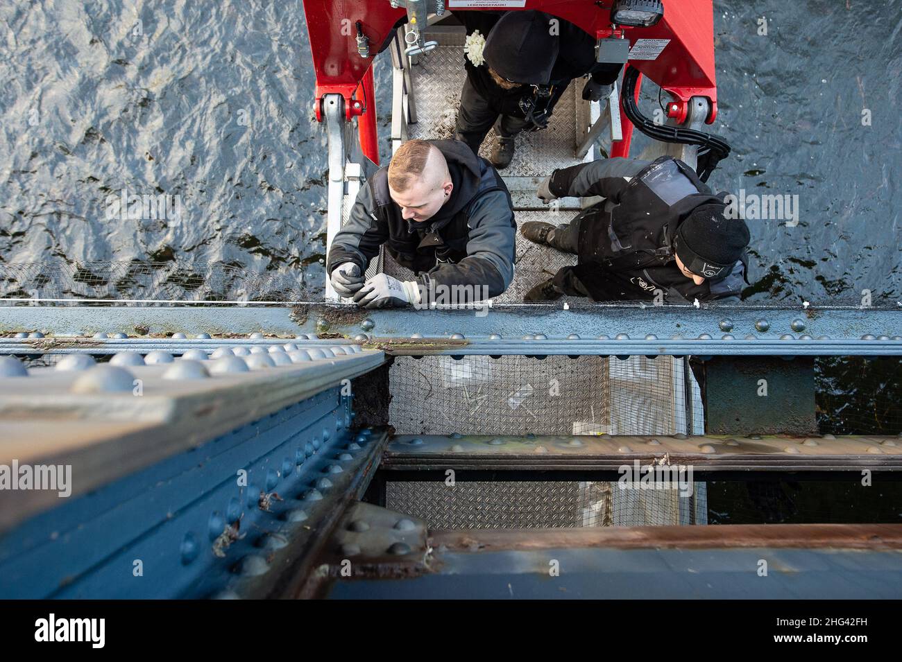 Vienenburg, Deutschland. 18th Januar 2022. Die Monteure Justin Parmar (l.) und Paul Sachs befestigen zur Vorbereitung des Neubaus ein Netz an der Oker Bridge. Dies soll verhindern, dass Vögel und Fledermäuse die Struktur als Brutstätte und Brutstätte nutzen. Während das Netz angeschlossen wird, wird die Fahrbahn bis zum 21. Januar 2022 für den Fahrzeugverkehr gesperrt. Quelle: Swen Pförtner/dpa/Alamy Live News Stockfoto