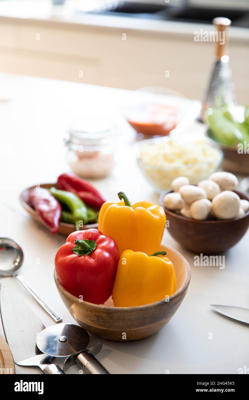 Bunte Paprika in Holzschale auf einer weißen Granitplatte. Textraum Stockfoto