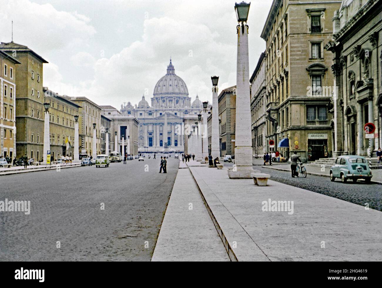 Die Via della Conciliazione (Straße der Schlichtung), Rom, Italien in c. 1960. Der Verkehr scheint in jenen Tagen ruhig zu sein. Die Straße verbindet Rom mit dem Petersplatz und der Basilika, Vatikanstadt (hinten). Die Straße wurde zwischen 1936 und 1950 gebaut. Der faschistische Diktator Benito Mussolini hat hier eine frühere Idee einer großen Durchgangsstraße wiederbelebt. Die Gebäude waren aus der Ausrichtung heraus, so dass die Illusion eines perfekt geraden Boulevards geschaffen wurde, wurden Fußgängerinseln ‘mit Reihen von Obelisken/Laternenpfosten gebaut. Dieses Bild stammt von einem alten Amateur 35mm Farbtransparenz – ein Vintage 1950/60s Foto. Stockfoto