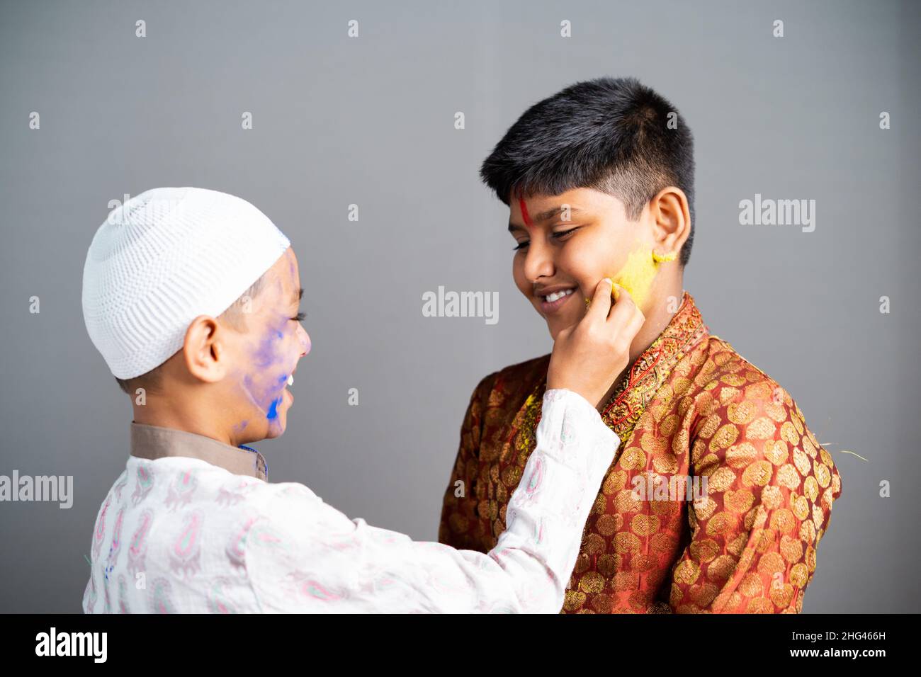 Multiethnische religiöse Kinder feiern holi durch die Anwendung von Farben auf grauen Hintergrund Gesicht - Konzept der kulturellen Festivals, Freundschaft und Einheit in Stockfoto