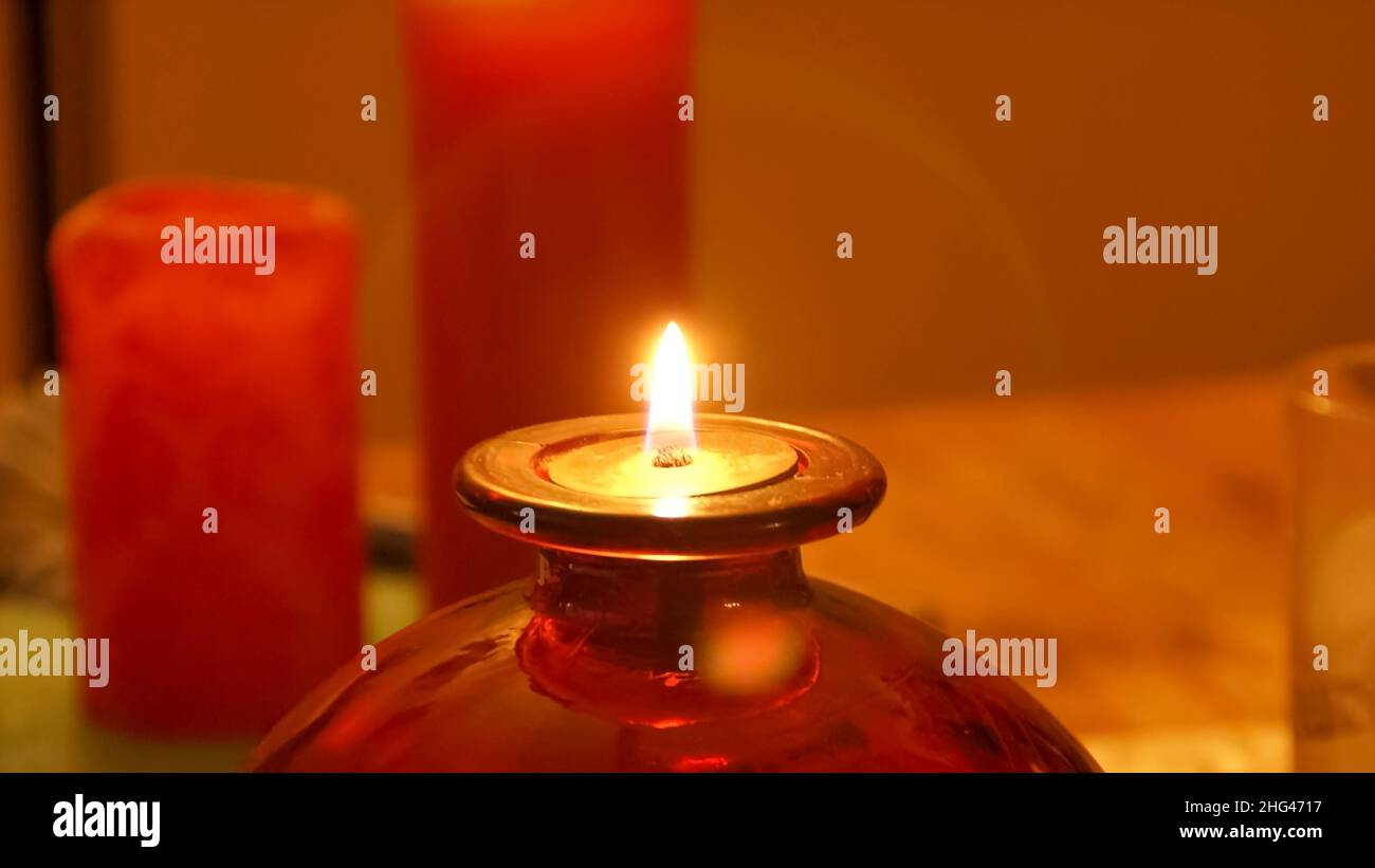 Schöne kleine Szene einer brennenden Öllampe mit Kerzen im Hintergrund. Stockfoto