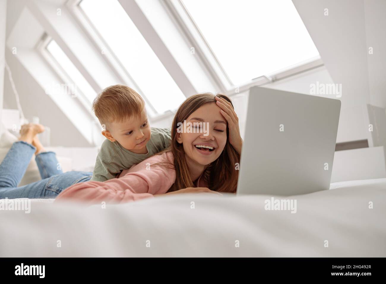 Glückliche Frau mit Laptop, während sie Zeit mit ihrem Baby verbringt Stockfoto