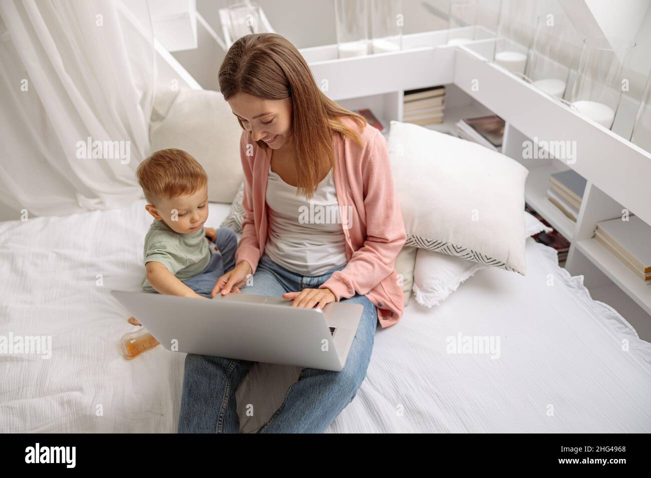 Glückliche junge Mutter mit ihrem Baby mit Latop Stockfoto