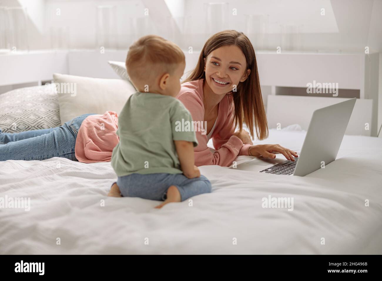 Glückliche Dame mit Laptop, während sie ihren kleinen Sohn ansieht Stockfoto