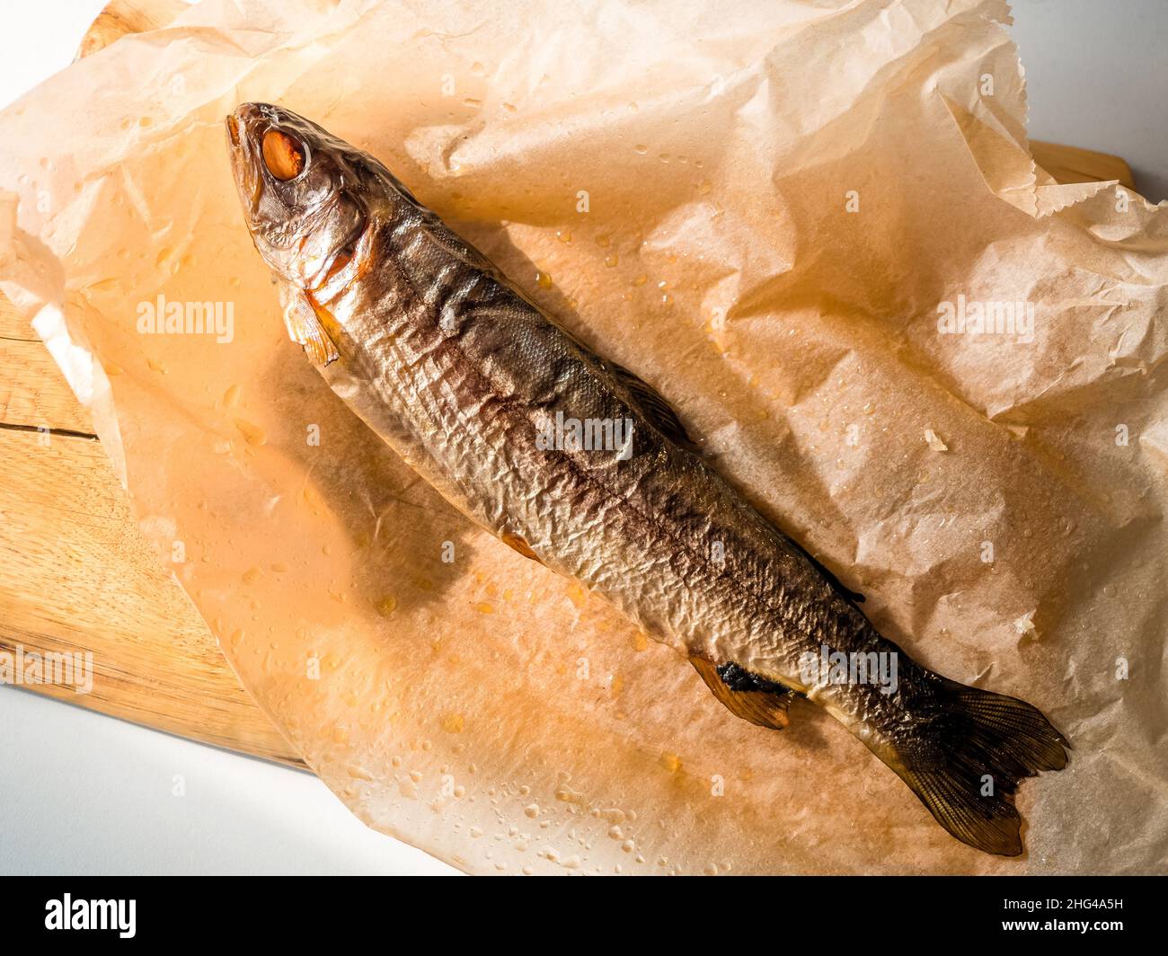 Geräucherter Fisch auf Papier, Draufsicht. Kalt geräucherter Forellenfisch mit Gewürzen, leckere Fischvorspeise Stockfoto