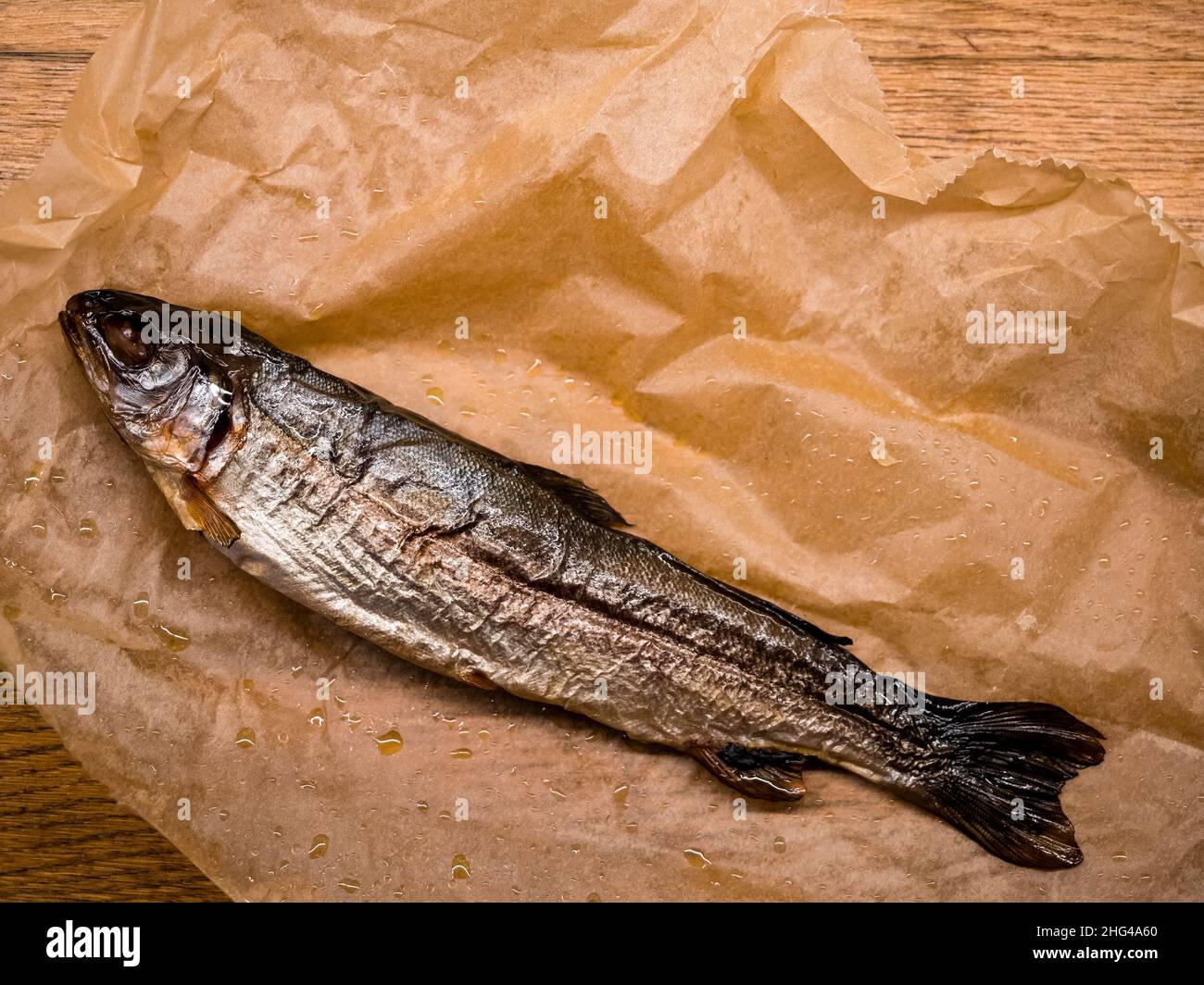 Geräucherter Fisch auf Papier, Draufsicht. Kalt geräucherter Forellenfisch mit Gewürzen, leckere Fischvorspeise Stockfoto