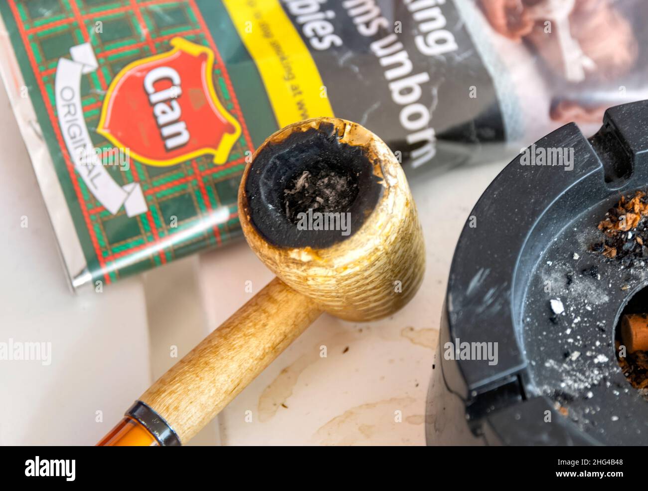 Pfeife auf weißem Holztisch mit Tabak und Aschenbecher Stockfoto