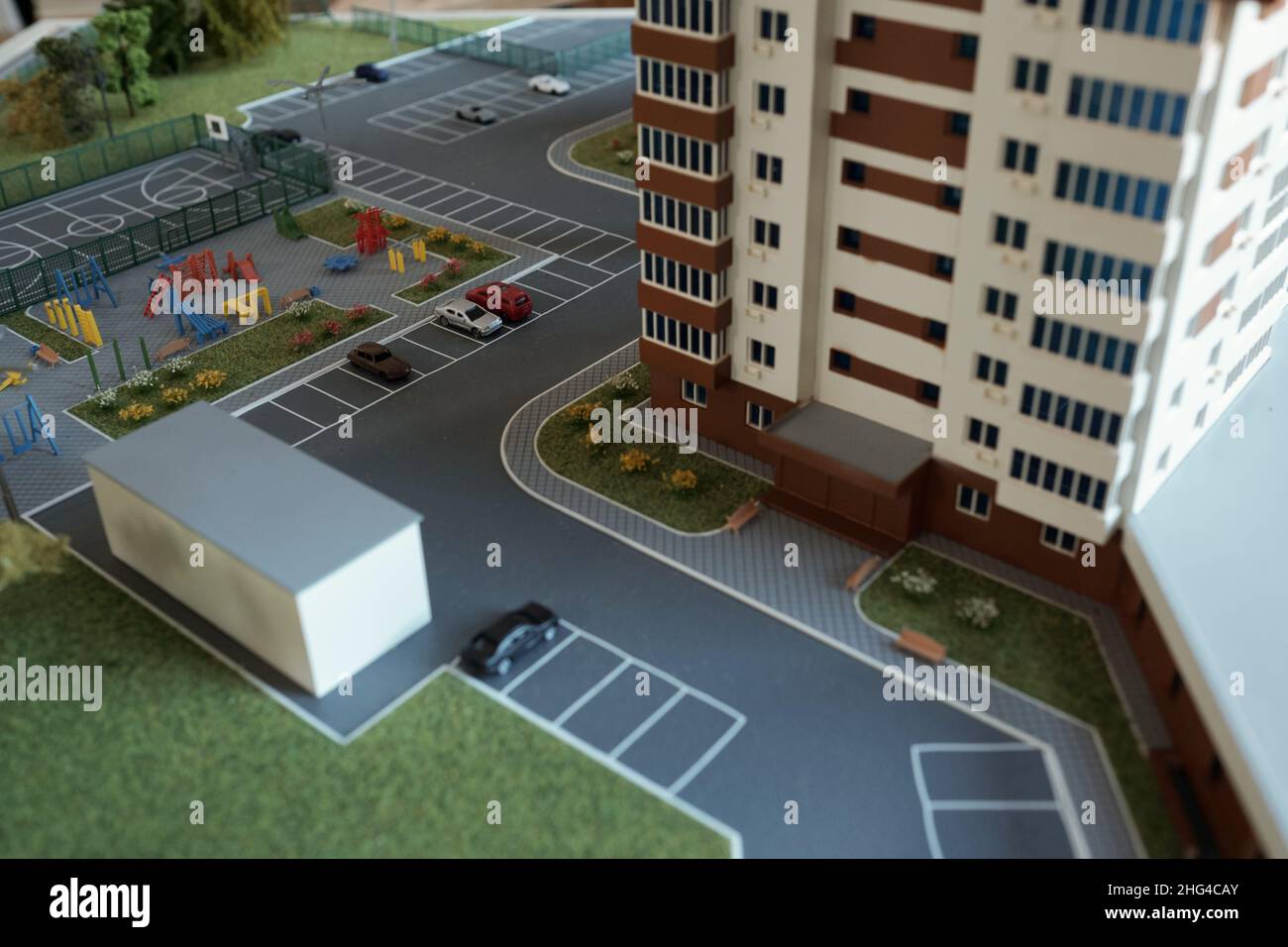 Layout des Wolkenkratzers umgeben von Hof mit Spielplatz, Fußballplatz, Parkplatz mit Autos und Rasen mit Blumen und Bäumen Stockfoto