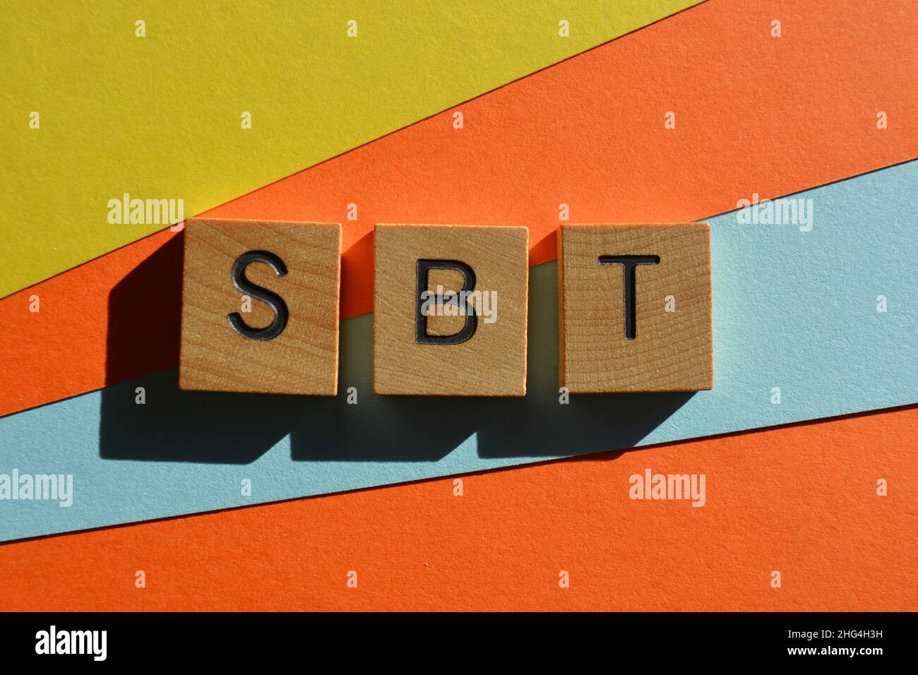 SBT, Akronym für Science Based Targets in hölzernen Buchstaben, isoliert auf mehrfarbigem Hintergrund Stockfoto