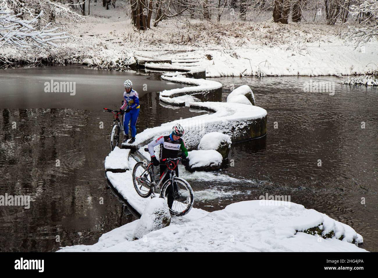 Radfahren im Winter. Die Radfahrer im Mountainbike-Getriebe überqueren den künstlichen Wasserfall auf dem Fluss Swisloch im Winter. Minsk. Weißrussland Stockfoto