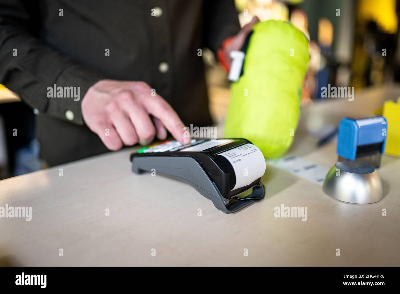 Der Verkäufer hält das Zahlungsterminal, während er den Beleg für den Abschluss des Kaufs hält. Nahaufnahme der Hände. Konzept von NFC, Geschäfts- und Bankgeschäften Stockfoto