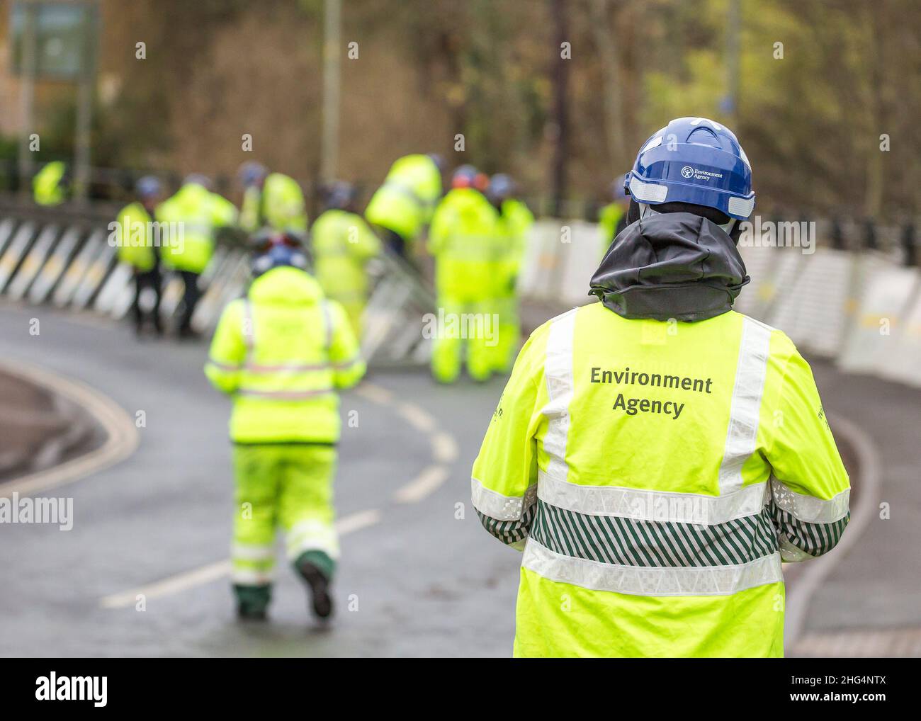 Rückansicht von Mitarbeitern des Umweltbundesamtes in Sichtjacken, die Hochwasserbarrieren errichten, Bewdley, Worcester, Großbritannien. Stockfoto