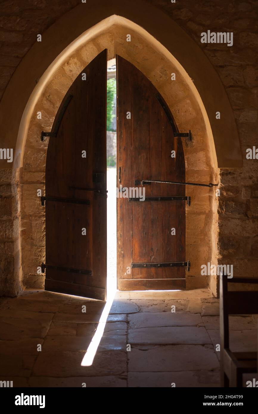 Alte Kapelle gewölbte Holztür leicht geöffnet lassen in einem Strahl von Sonnenlicht Stockfoto