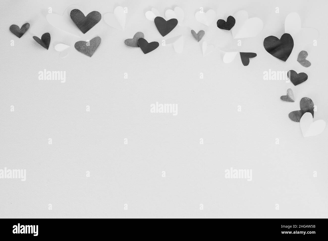 Valentinstag oder Hochzeit, Einladung, verstreut bemalt klein ausgeschnitten gefaltet schwarz-weißen Herzen auf weißem Leinwand Hintergrund, kopieren Raum Stockfoto