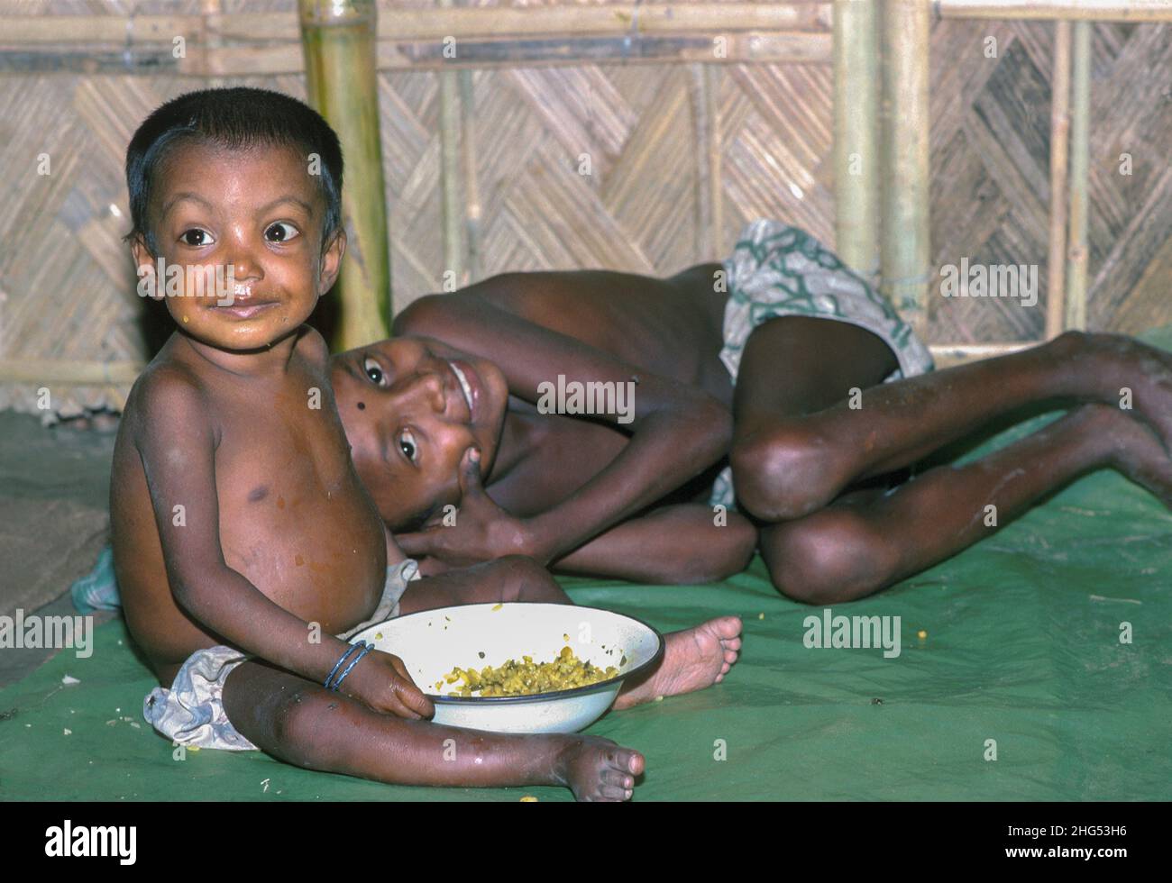Zwei glücklich aussehende Jungen mit einer Schüssel Nahrung in einer Notfütterungsstelle, die während schwerer Überschwemmungen für die Vertriebenen eingerichtet wurde. Jamalpur District, Bangladesch Stockfoto