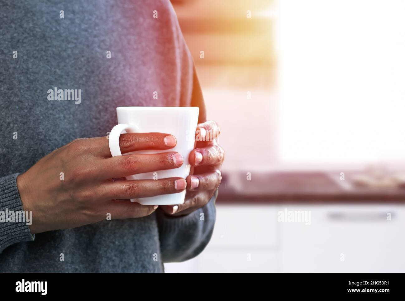 Hand eines Mannes, der eine Kaffeetasse in der Küche hält Stockfoto