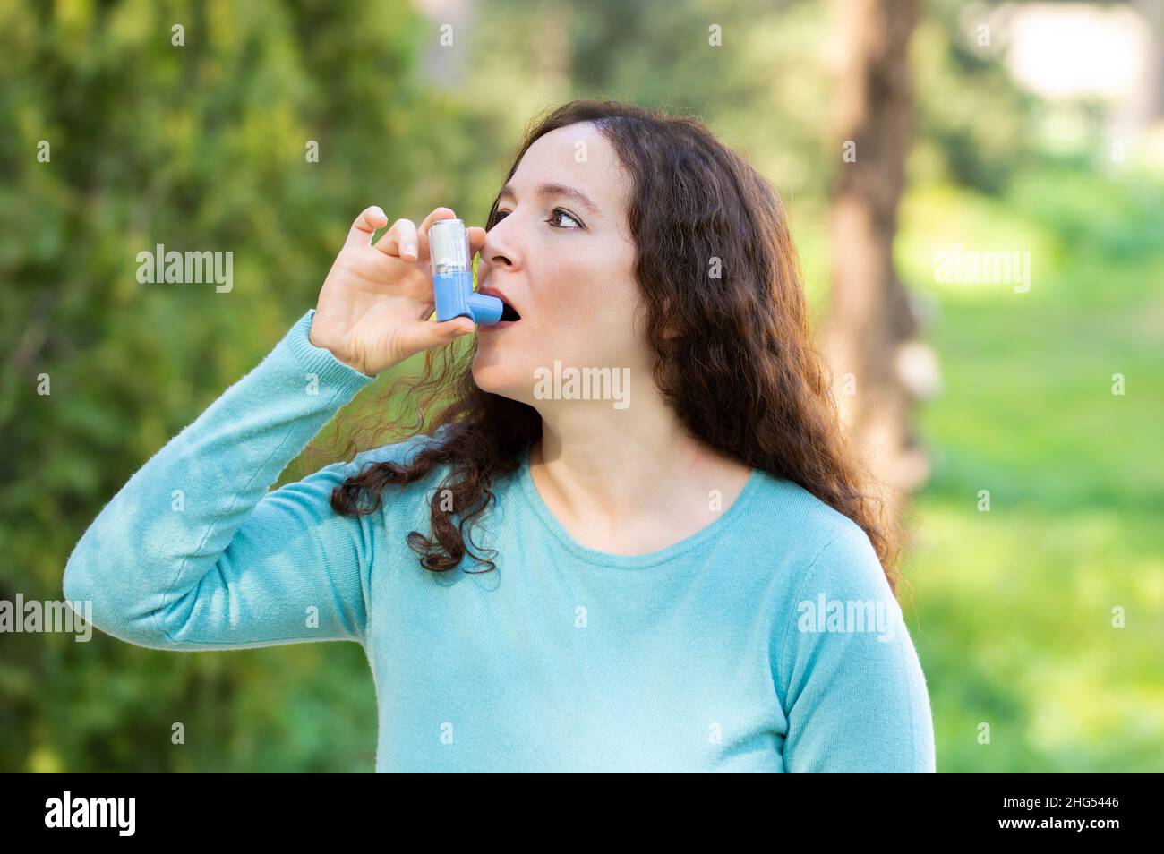 Die Frau verwendet einen Asthma-Inhalator in einem Park Stockfoto