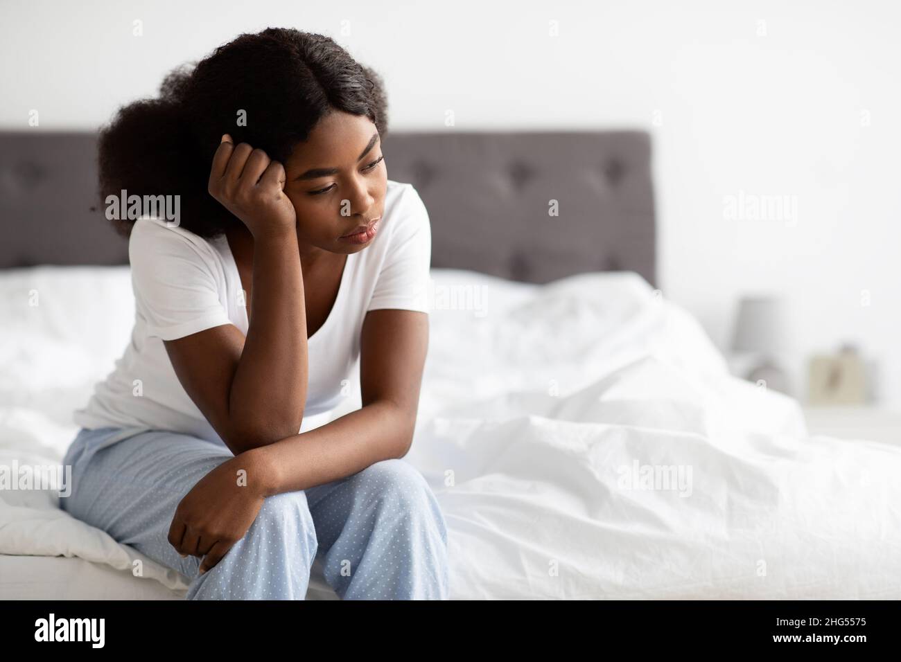 Depressive afroamerikanische Frau, die zu Hause auf dem Bett sitzt Stockfoto