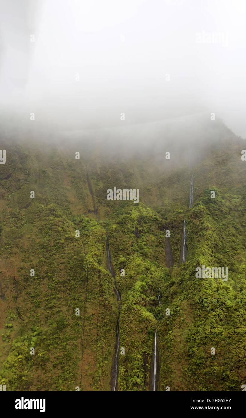 Eine Luftaufnahme der Caldera eines erloschenen Vulkans mit Vegetation und Wasserfällen, die über die Klippe im Waimea Canyon State Park in Kauai strömen, Stockfoto