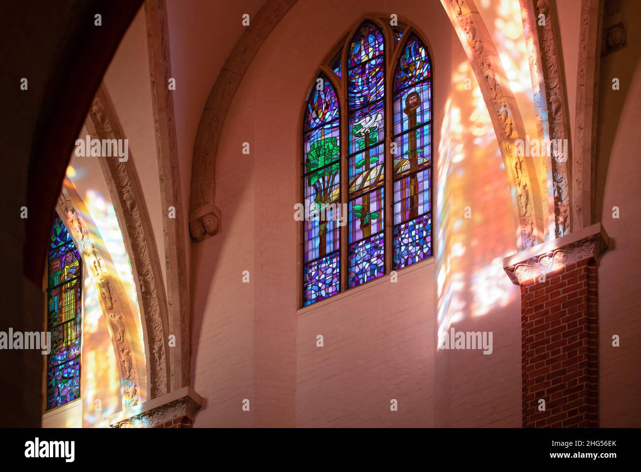 Die Blicke, die Darstellungen, das Lichtspiel, das durch die Strahlen der Sonne entsteht, die durch das Buntglasfenster in der Kirche hindurchgehen Stockfoto