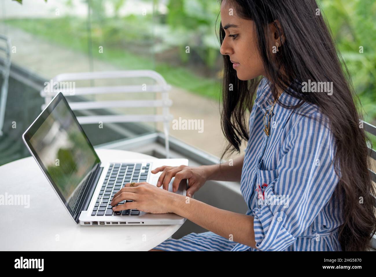 Junge lateinerin mit ihrem Laptop auf einer Cafeterrasse Stockfoto