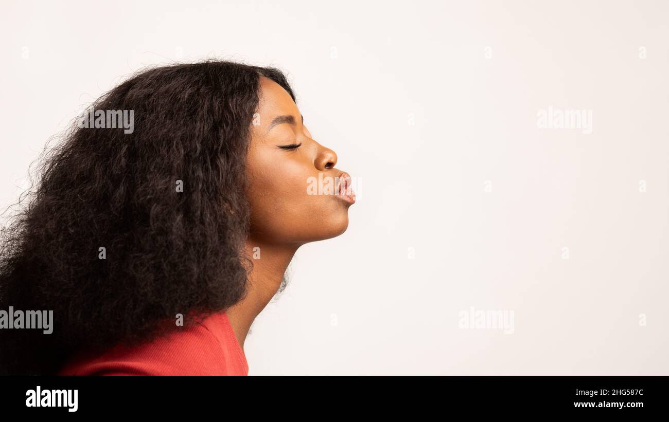 Profil Aufnahme Von Young Black Woman Pouting Lips Über White Studio Hintergrund Stockfoto