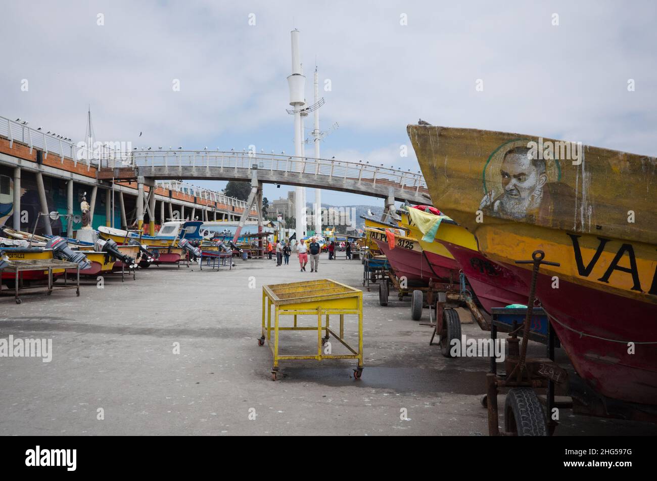 Valparaiso, Chile - Februar 2020: Motorboote stehen in der Nähe des Fischmarktes. Kleine Fischerboote mit Motor auf Kutschen. Porträt des heiligen Mannes an der Seite Stockfoto