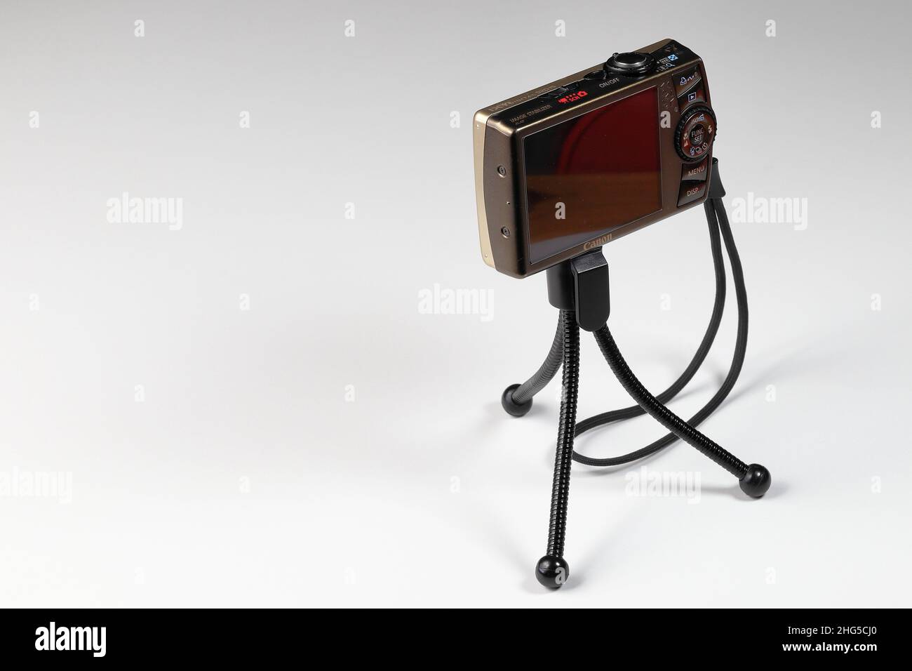 Digitale Kompaktkamera mit Handschlaufe und leerem Display auf kleinem Stativ isoliert auf weißem Hintergrund. Stockfoto