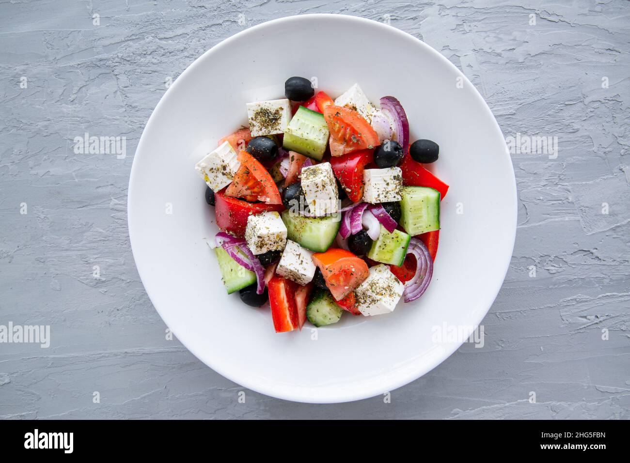 Frischer, leckerer griechischer Salat auf grauem Steinbeton-Hintergrund, Blick von oben. Stockfoto