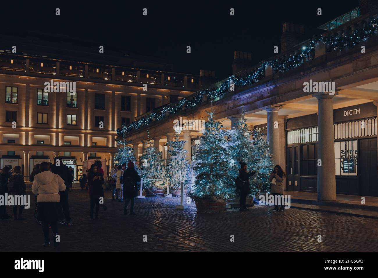 London, Großbritannien - 23. November 2021: Menschen, die an Weihnachtsbäumen vorbeigehen und Fotos von Weihnachtsbäumen auf dem Covent Garden Market machen, einem der beliebtesten Touristenattraktionen Stockfoto