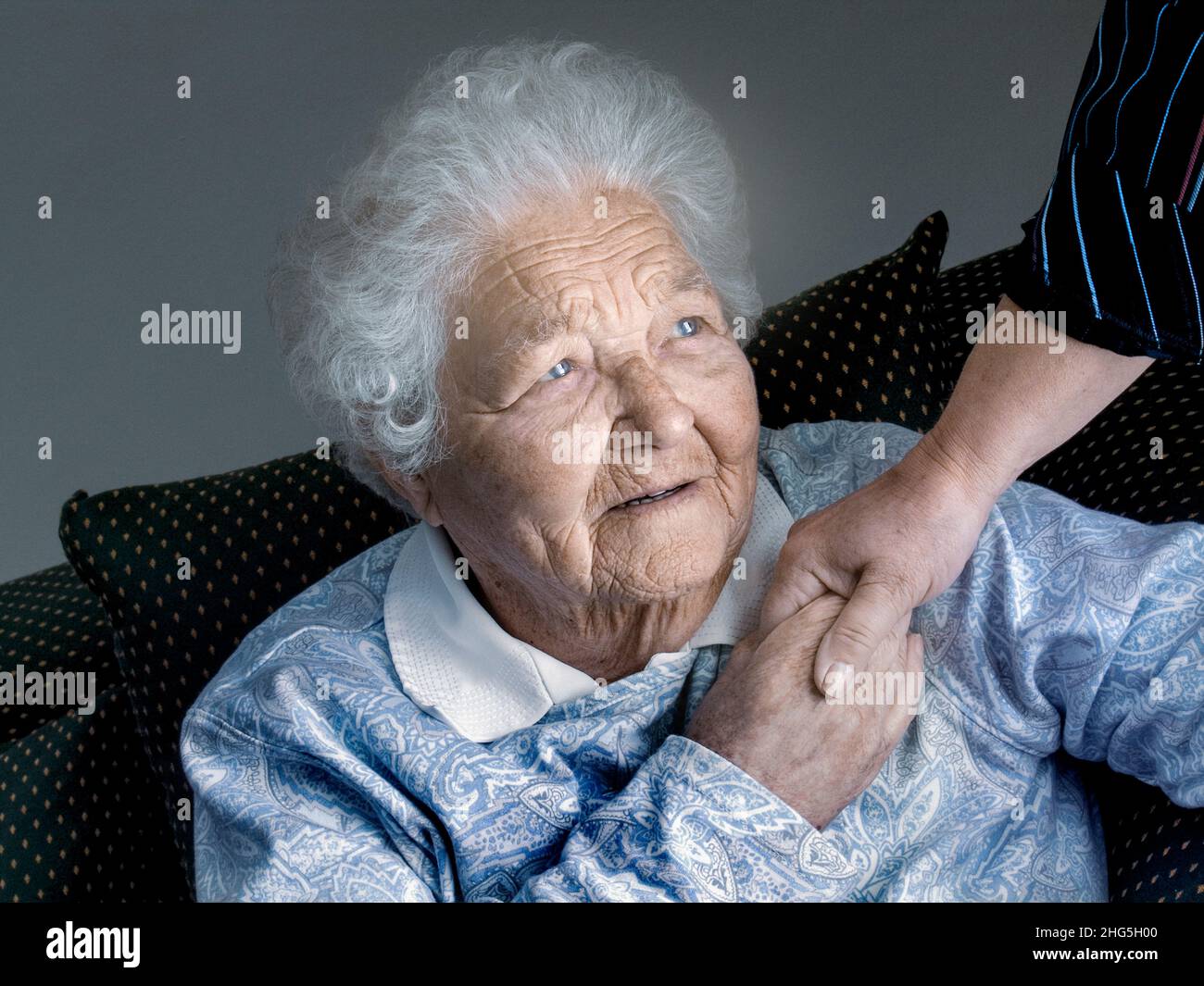 Ältere zufriedene unabhängige ältere ältere Dame hält die beruhigende Hand der Pflegefachkraft in ihrem Zimmer. Mit fürsorglicher Pflegepflege selbstbewusst in die Zukunft blicken Horizontales natürliches Licht im Innenraum Stockfoto